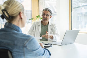 Arzt erklärt dem Patienten in der Klinik den medizinischen Bericht - UUF29223