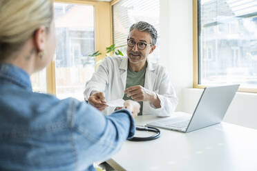 Doctor giving medical report to patient in clinic - UUF29224