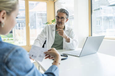 Arzt berät Patient beim Lesen eines medizinischen Berichts in der Klinik - UUF29225