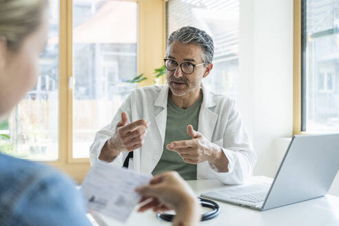 Doctor explaining medical report to patient in clinic - UUF29226