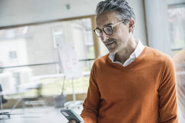 Älterer Geschäftsmann benutzt Smartphone im Büro - UUF29241