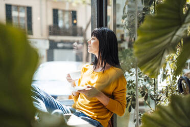 Nachdenkliche reife Frau sitzt mit einer Kaffeetasse in einem Café - JOSEF19727