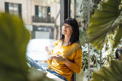 Smiling woman sitting with coffee cup in cafe - JOSEF19730