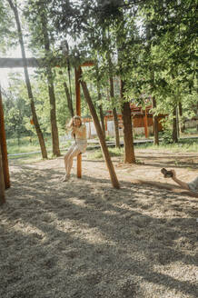 Happy girl playing on swing at park - ANAF01663