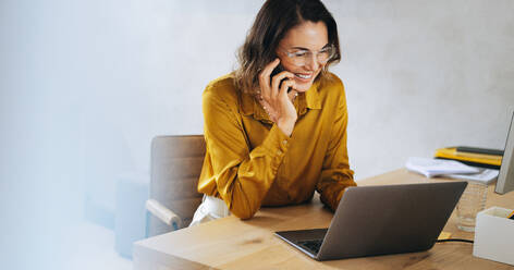 Successful businesswoman engages in a phone call from her office. Through effective communication, she makes business connections, discusses important matters, and ensures the success of her entrepreneurship. - JLPPF02054