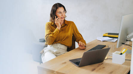 Businesswoman and web designer engages in a productive phone call. Female entrepreneur discussing important business matters with her clients, ensuring effective communication and successful outcomes. - JLPPF02055
