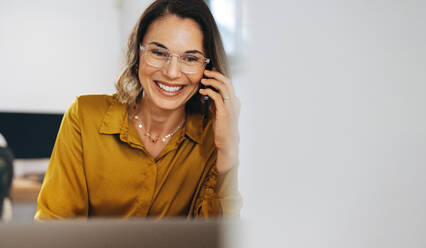 Happy businesswoman discussing a project on a phone call while working in her office. Successful entrepreneur making valuable business connections using her communication skills and professionalism. - JLPPF02058