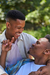 Happy, affectionate young gay male couple laughing and hugging - CAIF33416