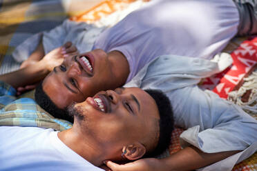 Close up happy, affectionate young gay male couple laying on blanket - CAIF33418