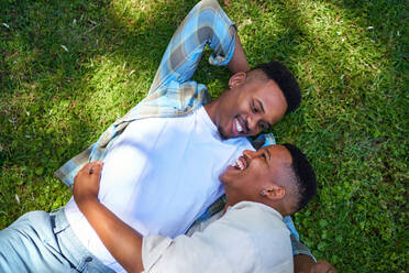 View from above happy, affectionate gay male couple laying in grass - CAIF33421