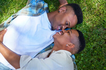 View from above happy, affectionate gay male couple laying in grass - CAIF33422