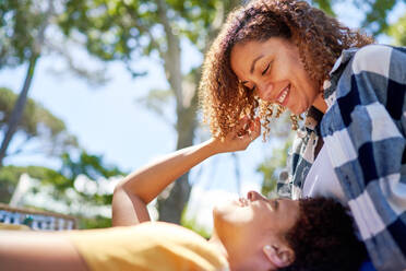 Happy lesbian couple cuddling in sunny summer park - CAIF33432