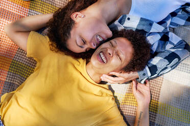 View from above happy lesbian couple laughing on blanket - CAIF33434