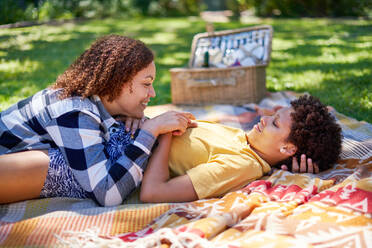 Happy lesbian couple relaxing, laying on picnic blanket in summer park - CAIF33435