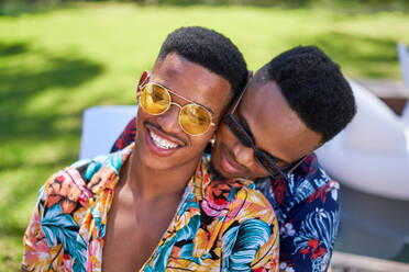 Happy young gay male couple in sunglasses hugging - CAIF33440