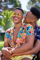 Happy young gay male couple in sunglasses hugging and laughing - CAIF33441