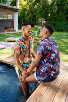 Happy young gay male couple at backyard summer swimming pool - CAIF33444