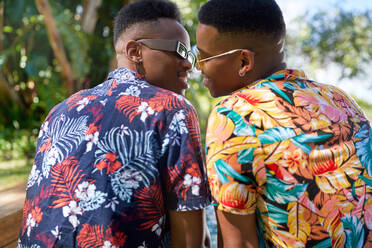 Affectionate gay male couple in Hawaiian shirts kissing - CAIF33448