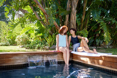 Happy lesbian couple relaxing at tropical summer swimming pool - CAIF33450