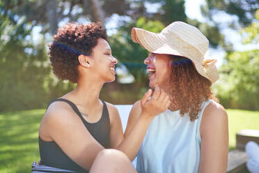 Happy, affectionate lesbian couple laughing in sunny summer backyard - CAIF33455