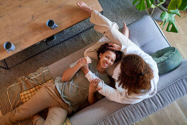 View from above happy lesbian couple cuddling on living room sofa - CAIF33477