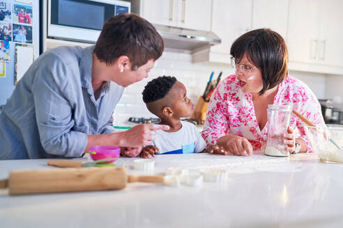Happy lesbian couple and son baking together in kitchen - CAIF33584