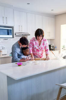 Lesbian couple and son baking, using rolling pin in kitchen at home - CAIF33588