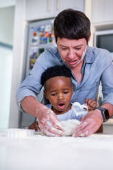 Mother and son baking heart-shape cookies in kitchen at home - CAIF33589