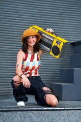 Portrait confident young woman holding boom box - CAIF33655