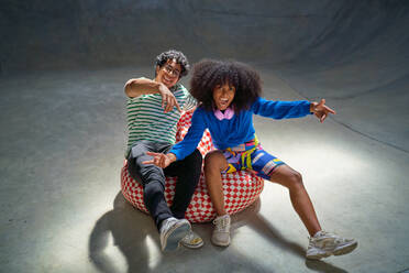 Portrait cool, enthusiastic young friends gesturing on bean bag chair - CAIF33666