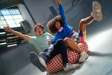 Portrait playful young friends falling, gesturing on bean bag chair - CAIF33667