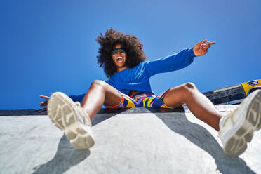 Portrait carefree young woman cheering at sunny sports ramp - CAIF33685