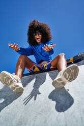 Portrait happy young woman gesturing at sunny sports ramp - CAIF33686