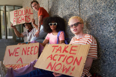 Portrait young friends holding equal rights signs at wall - CAIF33700