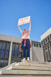 Young male protester holding change sign below government building - CAIF33702