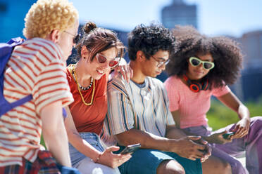 Young friends using smart phones in sunny city - CAIF33721