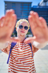 Portrait cool young man gesturing finger frame in sunny city - CAIF33735