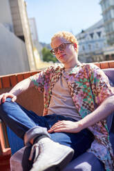 Portrait confident, cool young albino man on sunny rooftop - CAIF33740