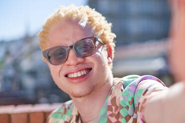 Nahaufnahme eines jungen, glücklichen Albino-Mannes, der für ein Selfie lächelt. - CAIF33744