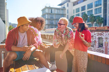 Happy young friends hanging out and eating pizza on sunny rooftop - CAIF33749