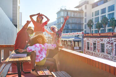 Portrait happy young friends cheering on sunny city rooftop - CAIF33753