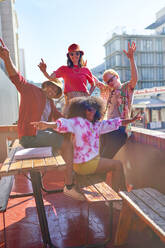 Portrait happy young friends cheering on sunny urban rooftop - CAIF33754