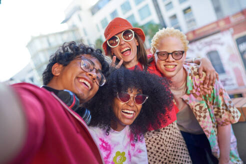 Eine Gruppe junger Freunde hält einen fröhlichen Moment auf einem städtischen Balkon mit einem Selfie fest. - CAIF33773