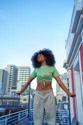 Portrait happy young woman on city balcony - CAIF33781