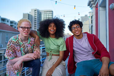 Portrait happy young friends on urban apartment balcony - CAIF33782