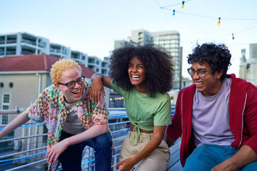 Happy young friends laughing on urban apartment balcony - CAIF33783