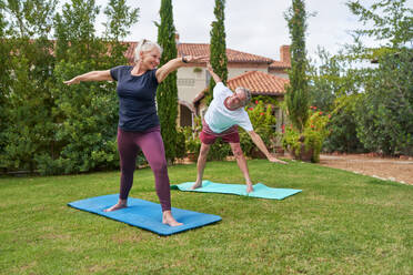 Happy, active senior couple practicing yoga in villa garden - CAIF33792