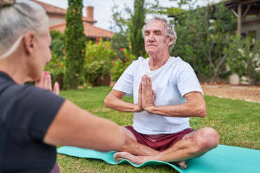 Serene senior couple meditating in summer garden - CAIF33795