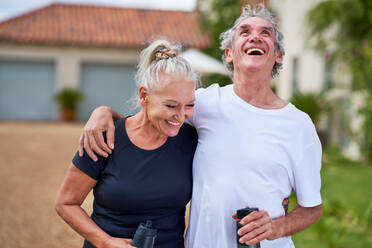 Happy, carefree senior couple with water bottles laughing - CAIF33800