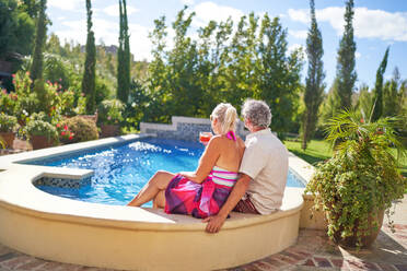 Senior couple relaxing at sunny summer swimming pool - CAIF33865